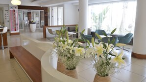 A modern hotel lobby with a reception desk, seating area, and large windows. - Calimera Side Resort - All inclusive (Manavgat)