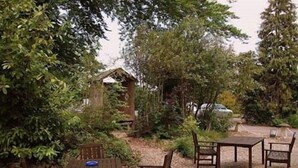 An outdoor seating area with a table and four chairs, surrounded by gravel and greenery. - Fieldways (Trowbridge)