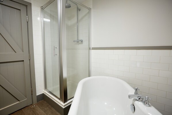 Un baño con cabina de ducha de vidrio, una bañera blanca y una puerta que da a otra habitación.
