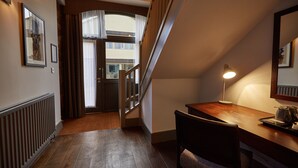 A hotel hallway with a wooden floor, a desk with a lamp, and a staircase leading to an upper floor. - Kings Head Masham by Chef and Brewer Collection (Ripon)