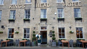 A stone building with "King's Head Hotel" signage, pub dining rooms, and outdoor seating with tables and chairs. - Kings Head Masham by Chef and Brewer Collection (Ripon)