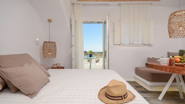 Un dormitorio con una cama, una mesa con frutas y vistas al exterior.