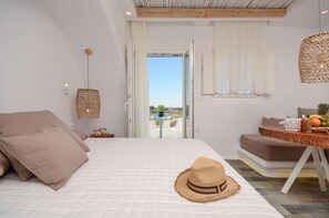 A bedroom with a bed, a table with fruits, a hat, and a view through a door. - Naxos Island Escape (Naxos)