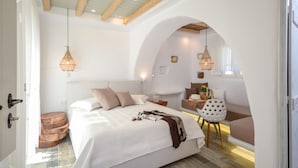 Un dormitorio con una cama grande, vigas de madera y una zona de estar acogedora con una mesa y sillas.