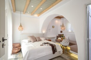 Un dormitorio con una cama grande, vigas de madera y una zona de estar acogedora con una mesa y sillas.
