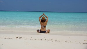 Una persona sentada en la playa mirando al océano.