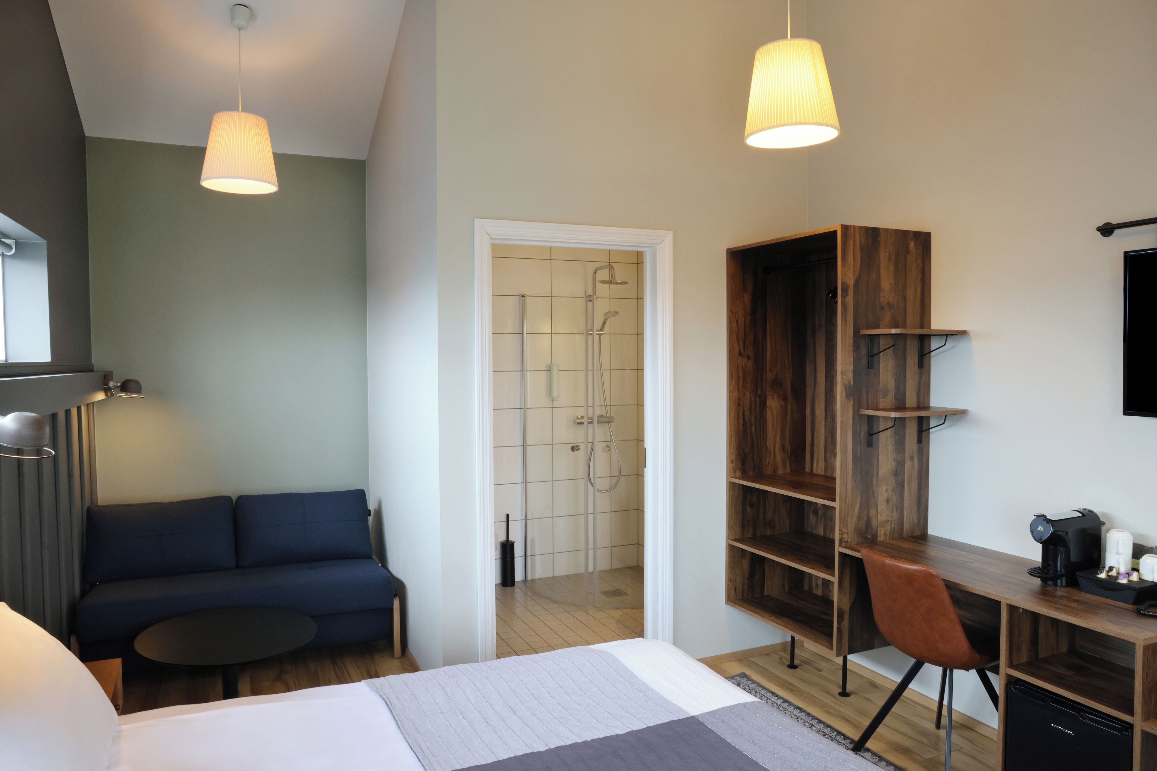 Une chambre d’hôtel moderne équipée d’un lit, d’un canapé, d’un bureau et d’un espace douche.