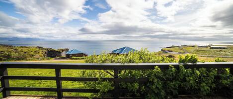Una terraza de madera con vista al mar y edificios a lo lejos.