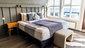A bedroom with a bed, bedside table, and a view of the outside through a window. - Fosshotel Hellnar (Hellnar)