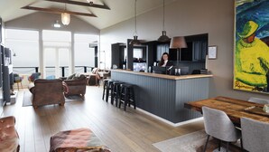 A spacious living area with a wooden dining table, bar stools, and a kitchen area with a bar counter. - Fosshotel Hellnar (Hellnar)