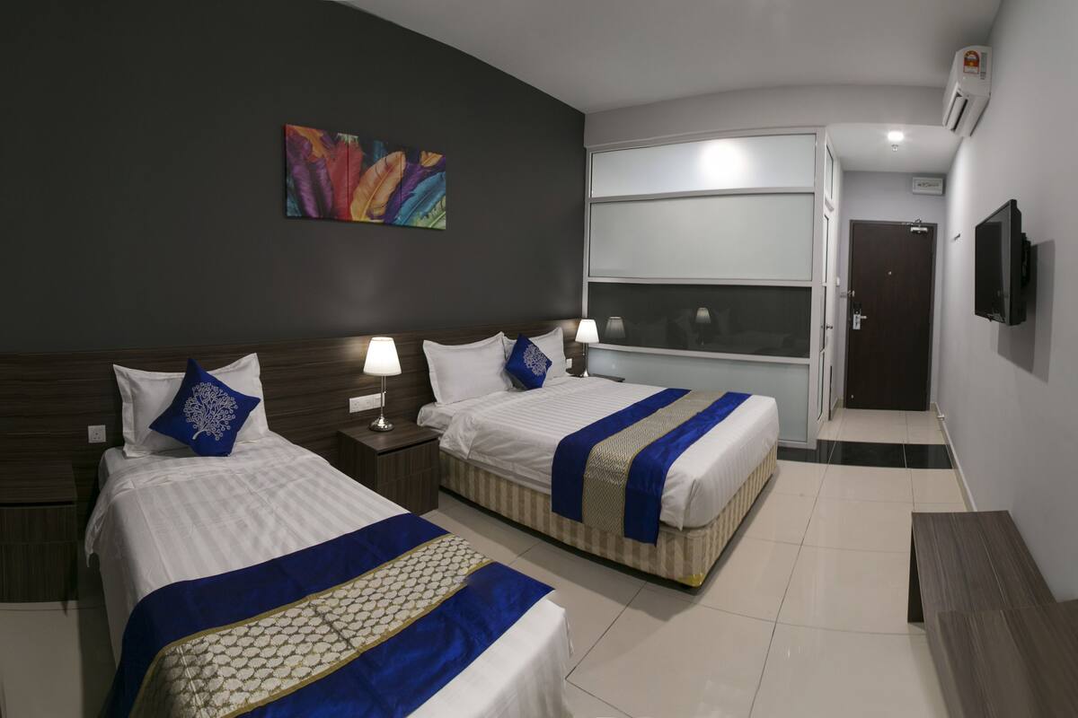 Une chambre d’hôtel avec deux lits, une grande fenêtre, un tableau au mur et un appareil de climatisation.