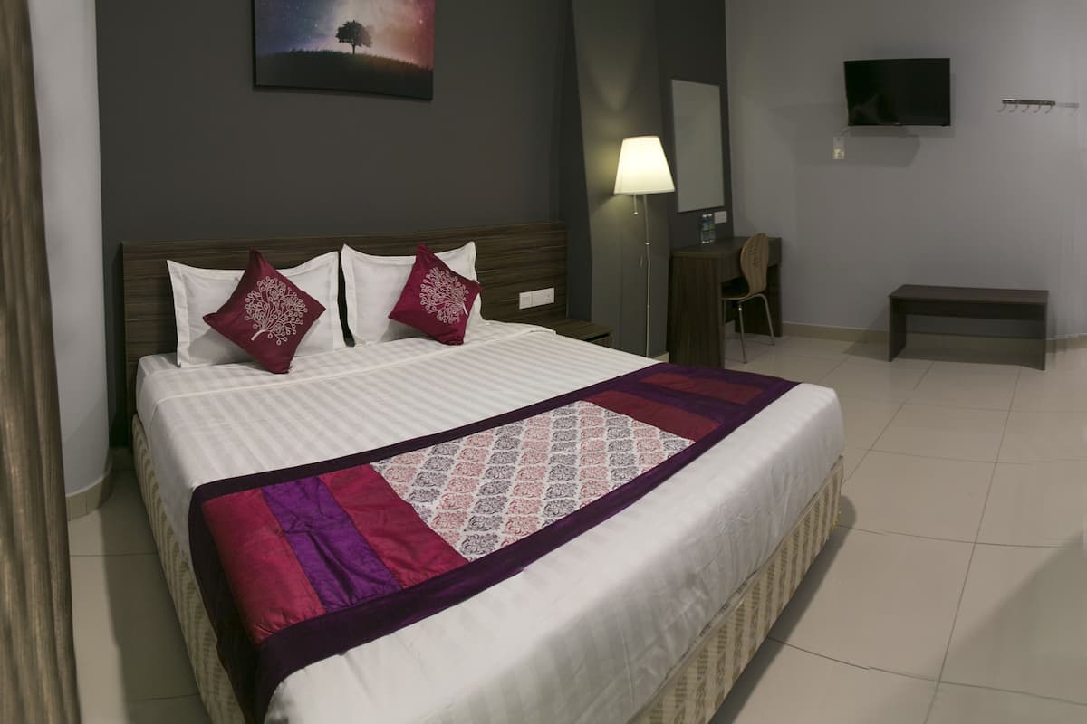 Une chambre d’hôtel avec un grand lit, un bureau, une chaise, une télévision et un tableau au mur.