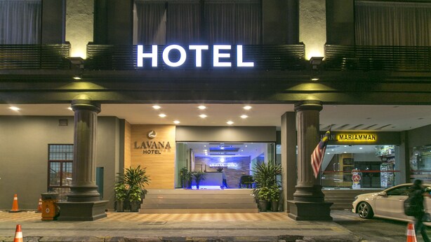 Entrada de hotel com uma placa grande 'HOTEL', um balcão de recepção e uma bandeira americana.