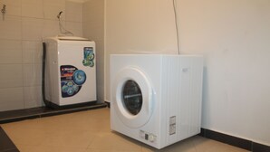 Máquina de lavar e secar compacta, branca, numa casa de banho com azulejos limpos.