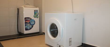 A compact, white washing machine and dryer unit in a clean, tiled bathroom.