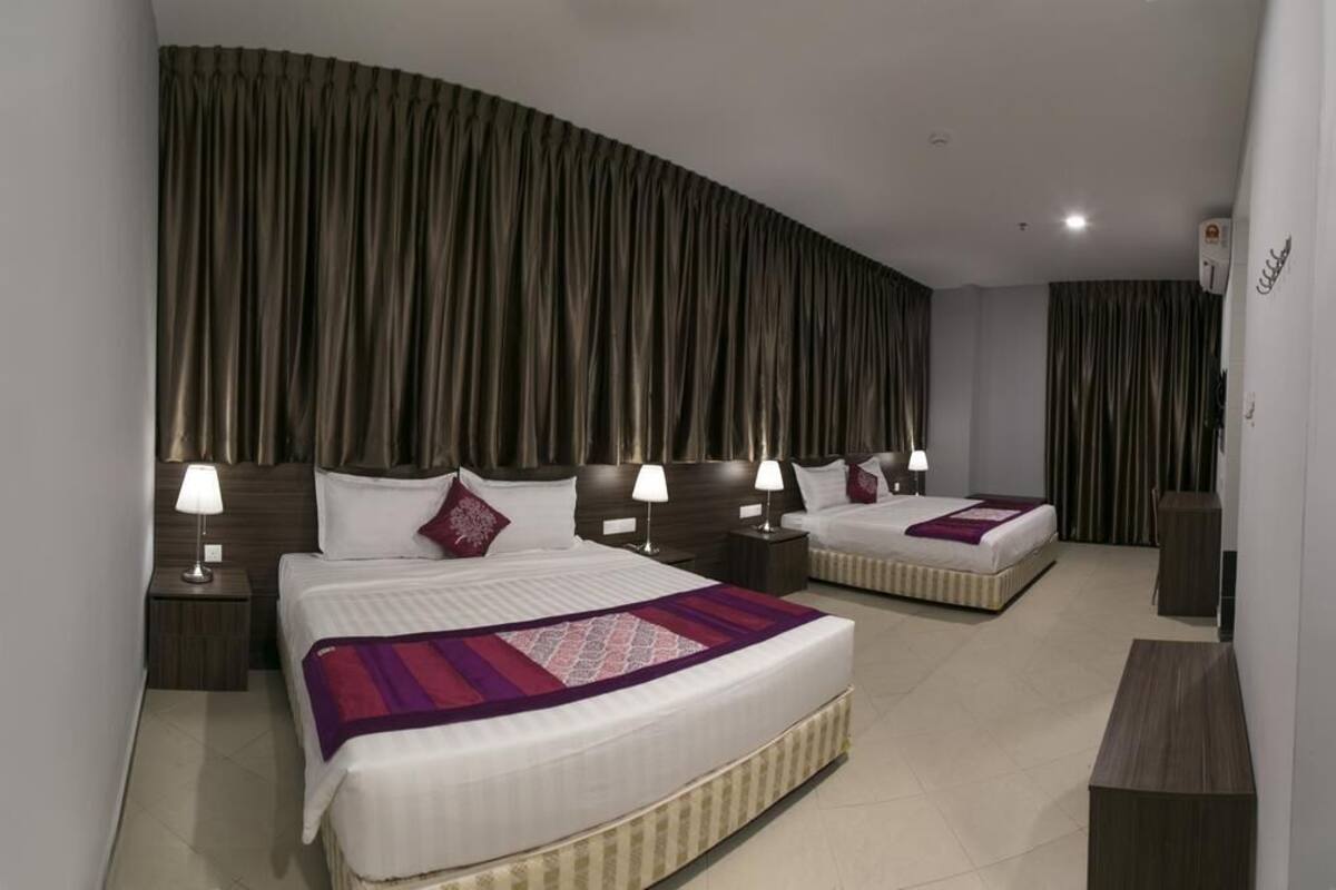 Une chambre d’hôtel avec deux lits, des rideaux foncés et des lampes de chevet.