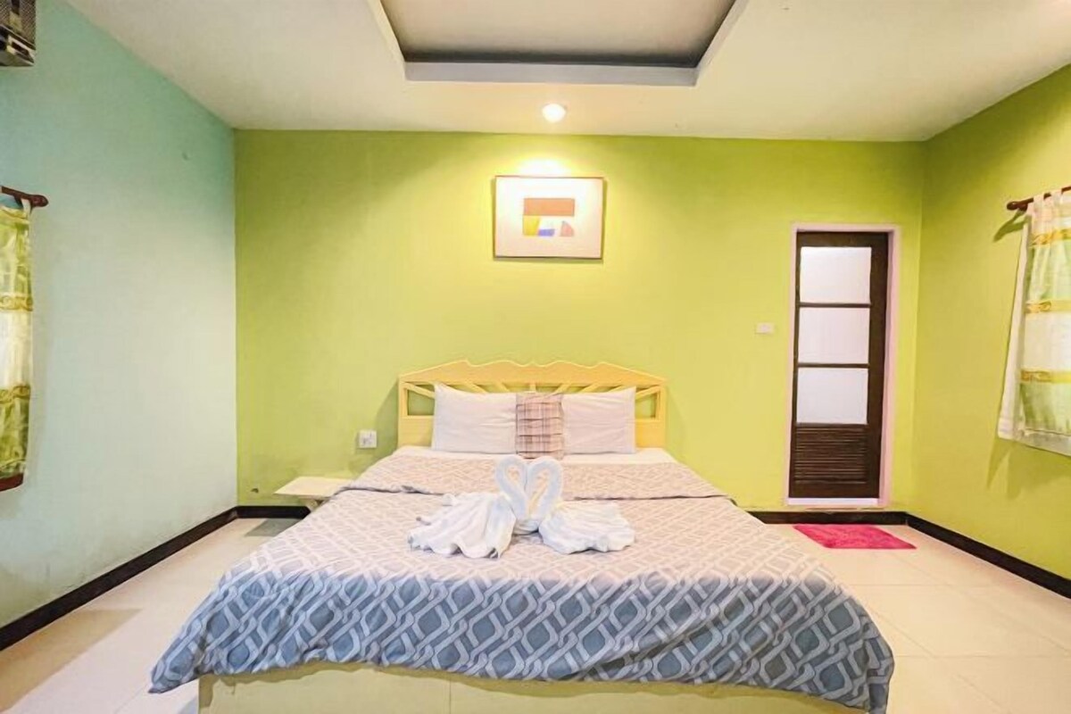 A bedroom with a bed, a nightstand, a framed picture on the wall, and a door.