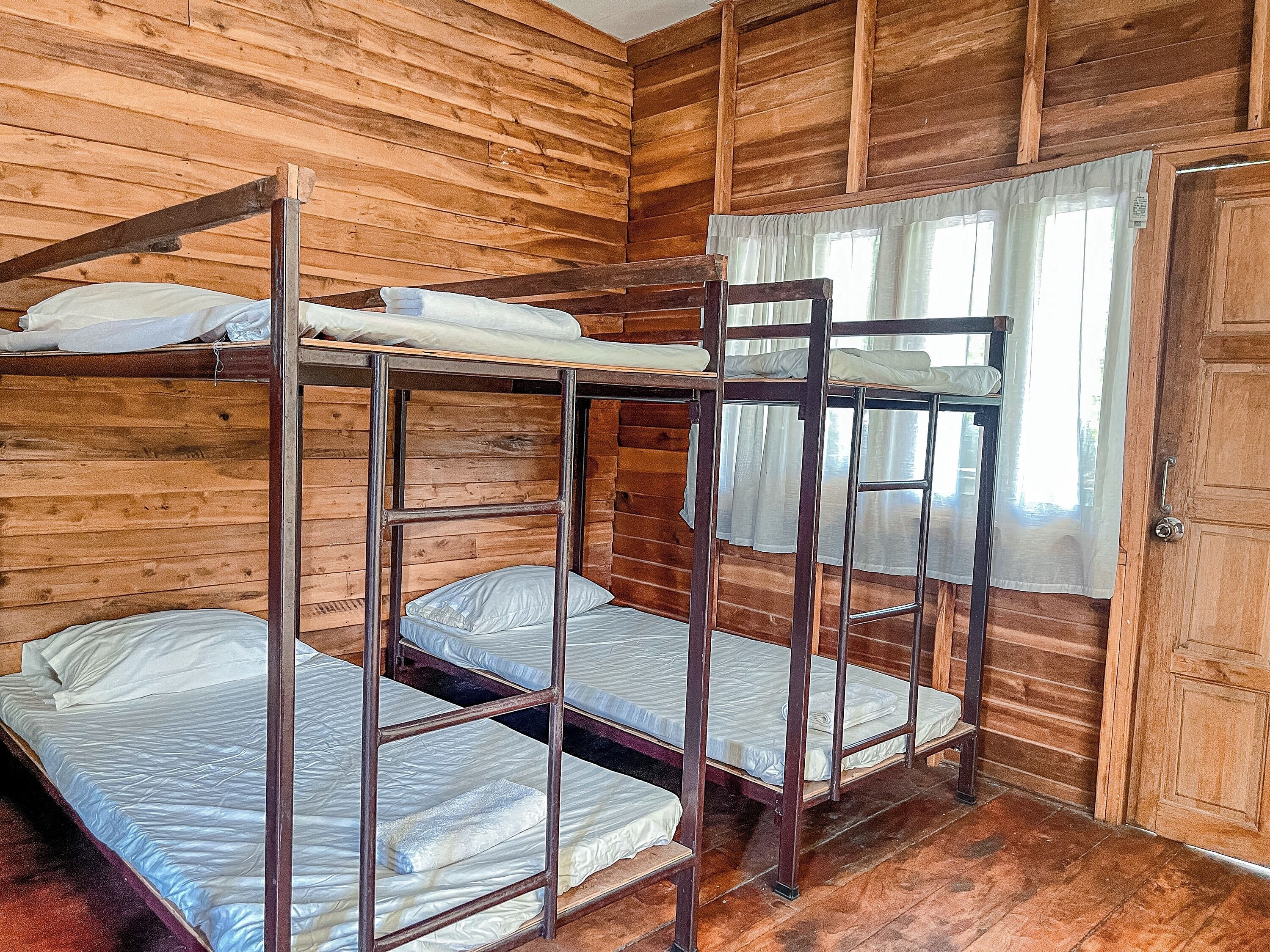 Habitación con literas, paredes de madera y una ventana con cortinas.