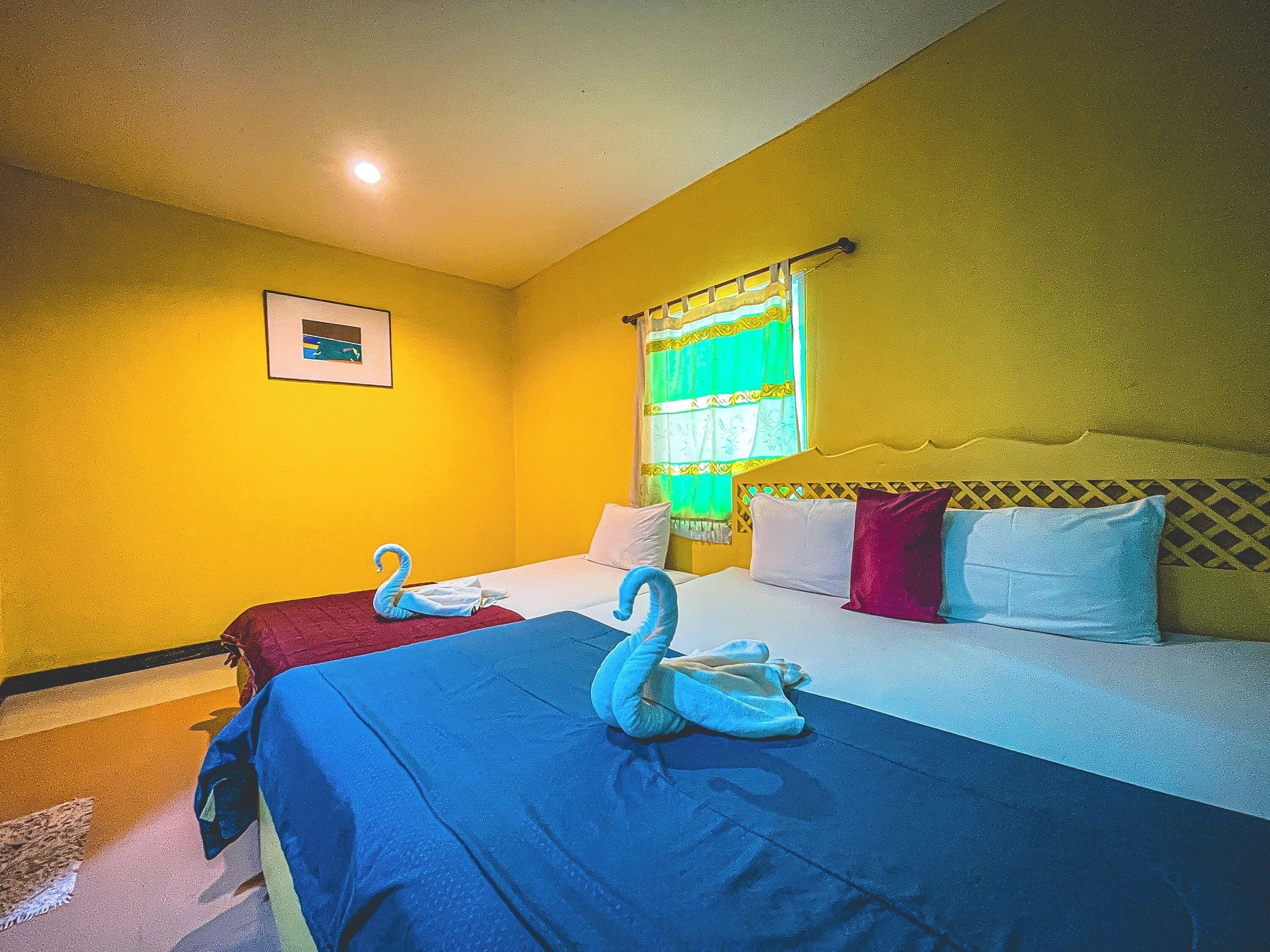 A hotel room with two beds, a framed picture on the wall, and a window with curtains.