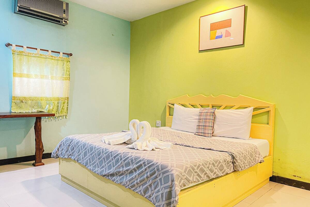 A room with a bed, a small table, and a window with curtains.