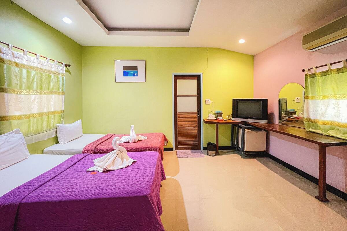 A hotel room with two beds, a television, a small table with a mirror, and a picture on the wall.
