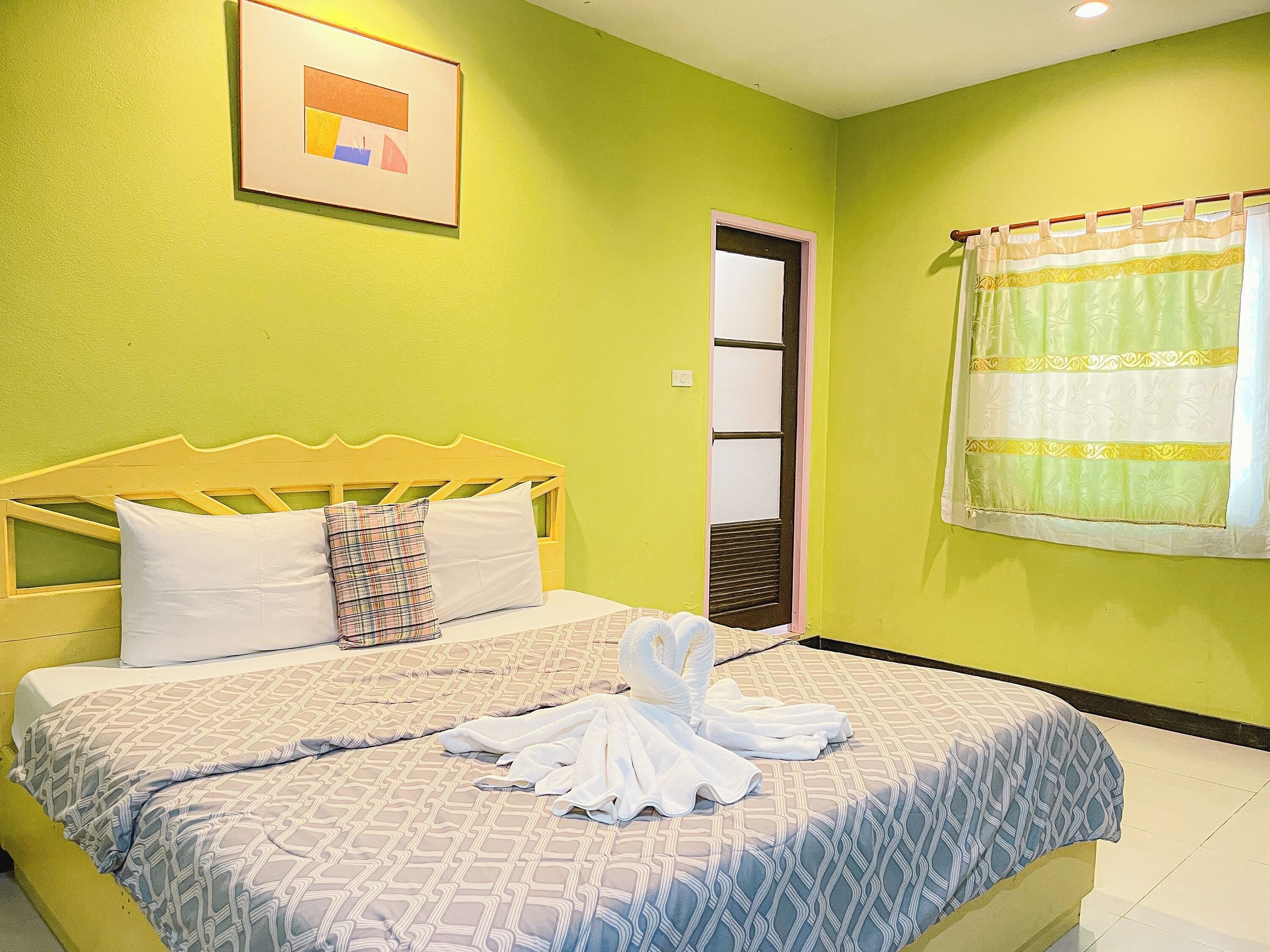 Una habitación con cama, puerta y ventana con cortinas.