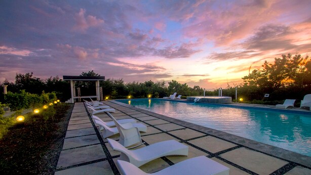 Un área de piscina con sillones reclinables y un pabellón.