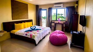 Una habitación de hotel con cama, escritorio, silla, televisor y aire acondicionado.