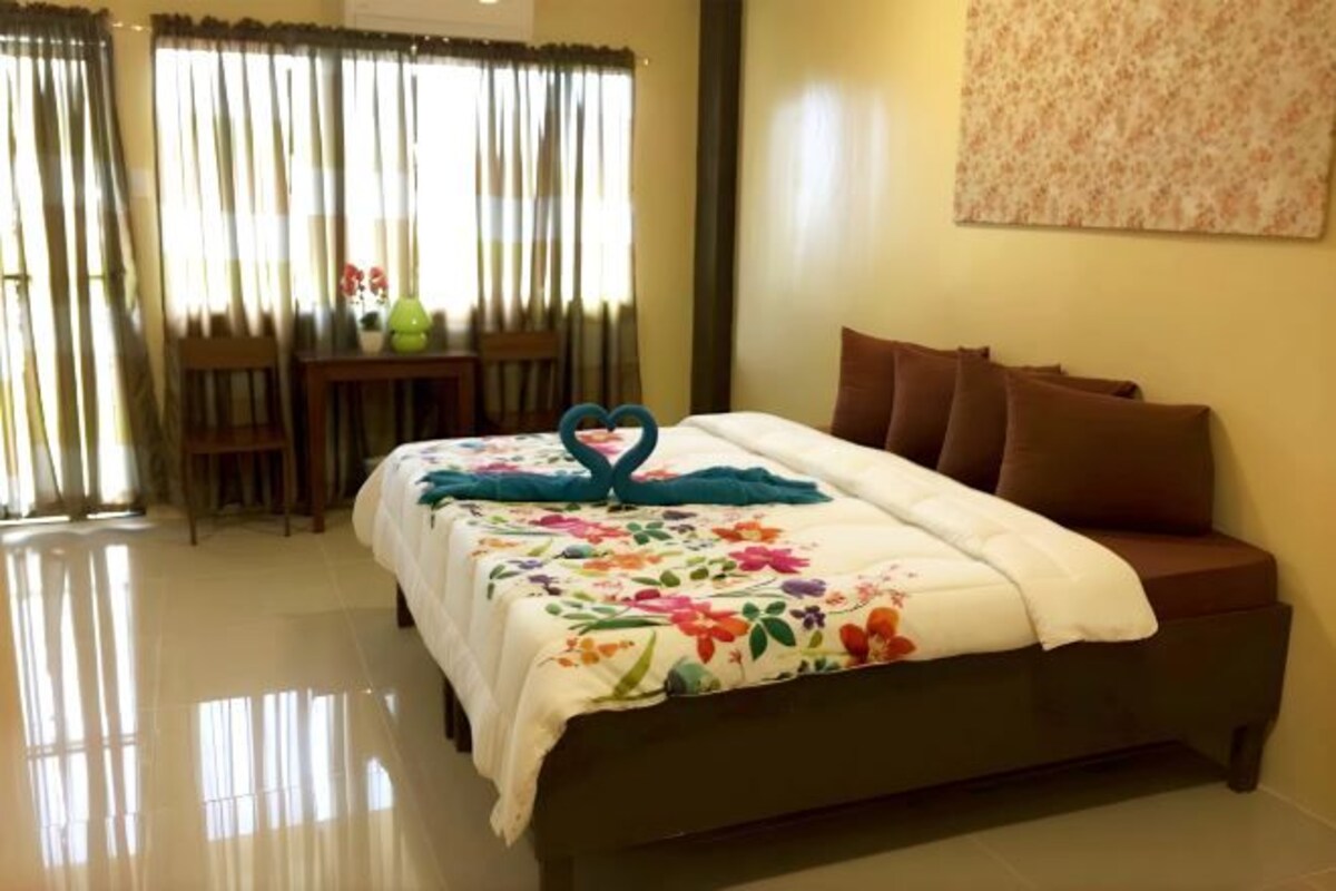 A hotel room with a bed, a table with chairs, and a window with curtains.
