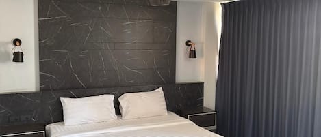 Ein modernes Schlafzimmer mit einem großen Bett, einem dunklen Marmorkopfstück und einer Kristallleuchtre.