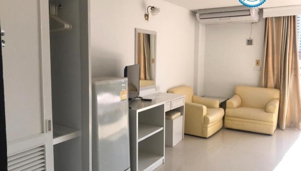 A modern hotel room with a desk, a sofa, a wardrobe, and a mirror.