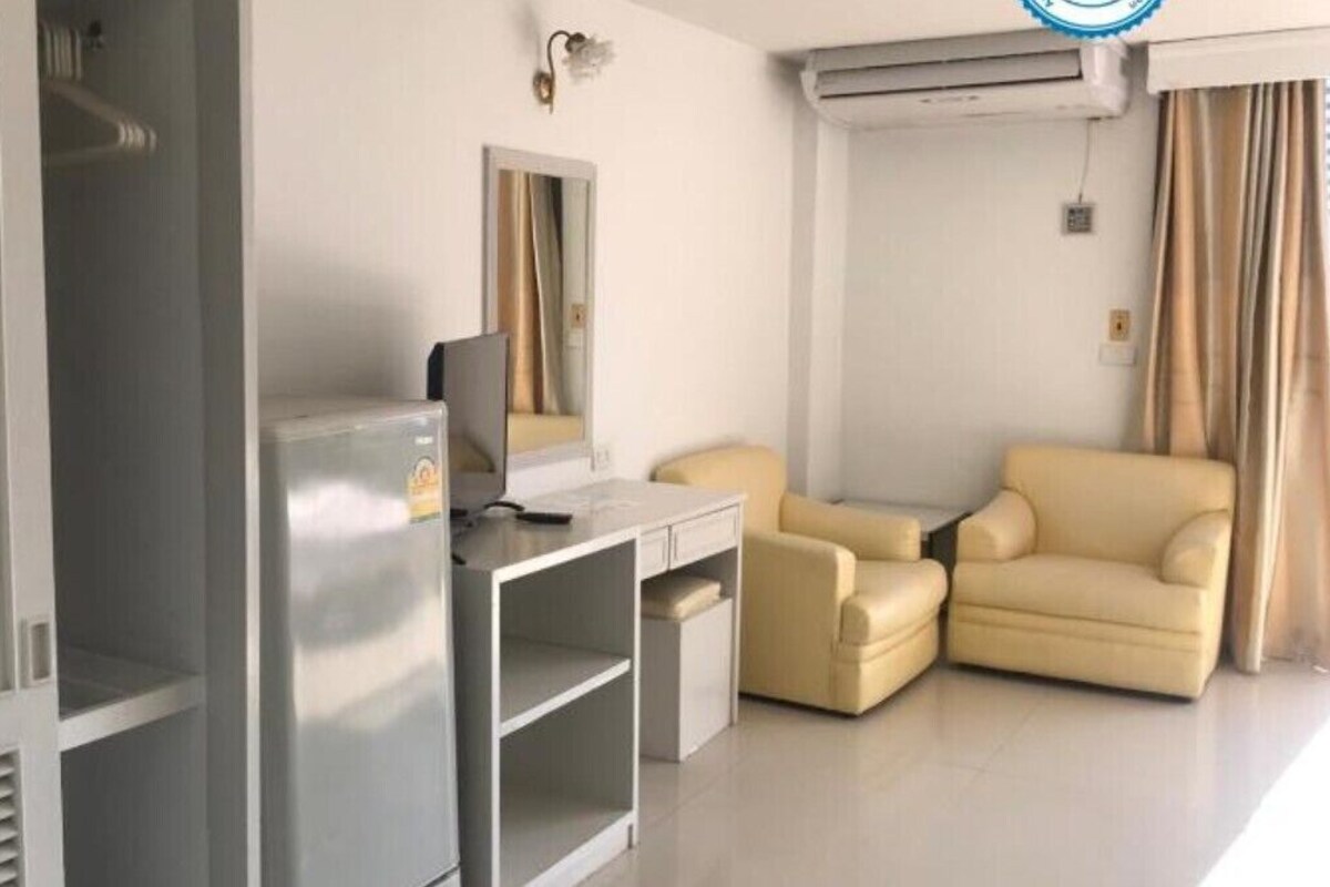 A modern hotel room with a desk, a sofa, a wardrobe, and a mirror.