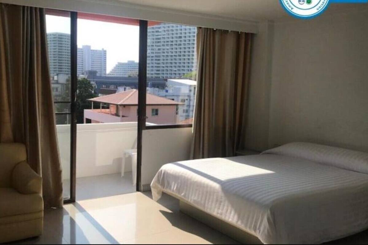 Een hotelkamer met een bed, een sofa, een schuifdeur en uitzicht op gebouwen.