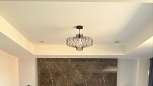 Ein modernes Hotelzimmer mit einem großen Bett, einem Marmorkopfstück, zwei Nachttischen, einer Chandelüster und einem Paar Handtüchern auf dem Bett.