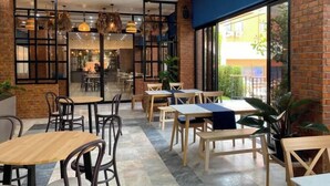 Ein Restaurant mit Ziegelwänden, Holztischen und hängenden Lampen.