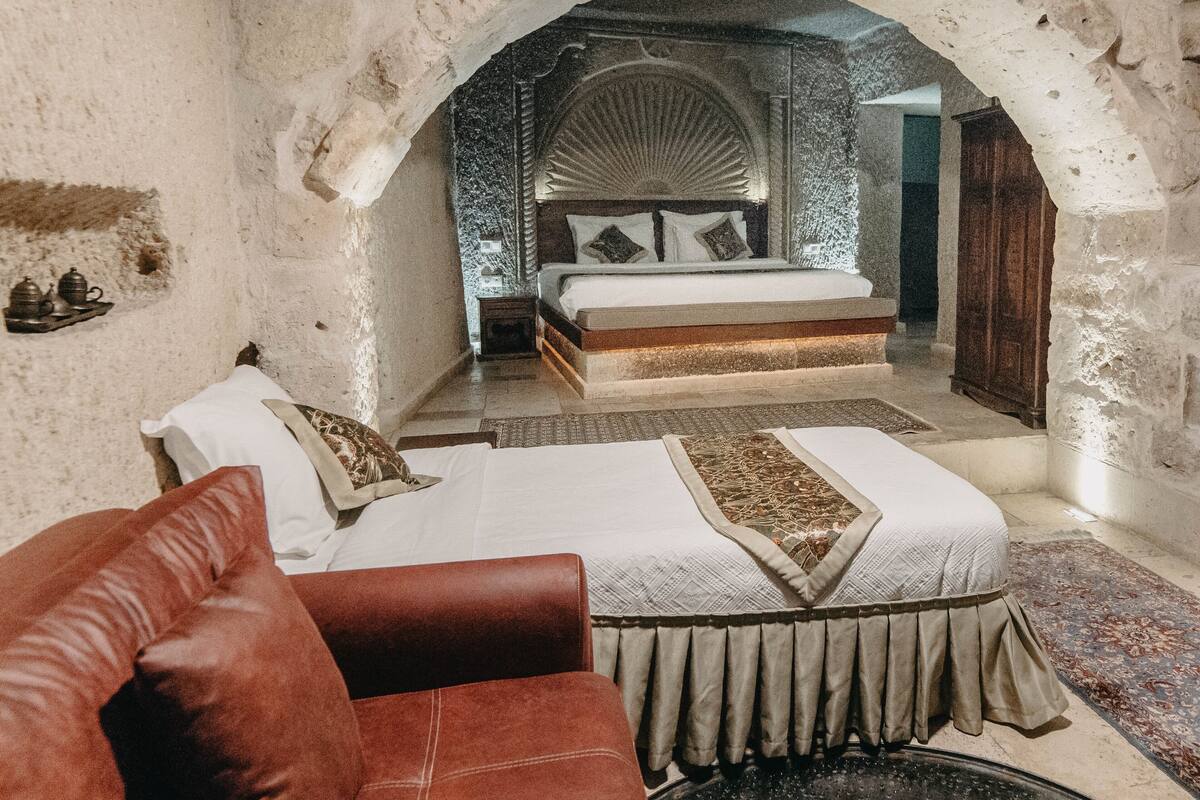 Une pièce comprenant un grand lit, un canapé et une porte en arc donnant sur une autre pièce.