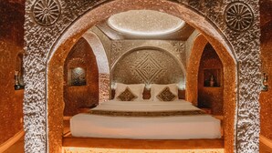 Una habitación con una cama grande, arcos decorativos y un techo ornamentado.