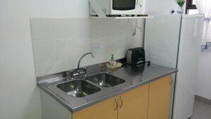 A compact kitchen with two stainless steel sinks, a microwave, and a toaster on the countertop. - Apart Hotel Tierra del Fuego (Ushuaia)