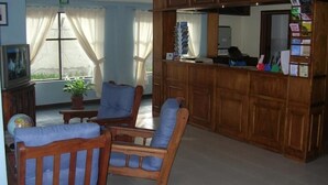 A living room with wooden furniture, a television, and a potted plant. - Apart Hotel Tierra del Fuego (Ushuaia)