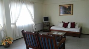 A room with a bed, a TV, a table, and a chair.