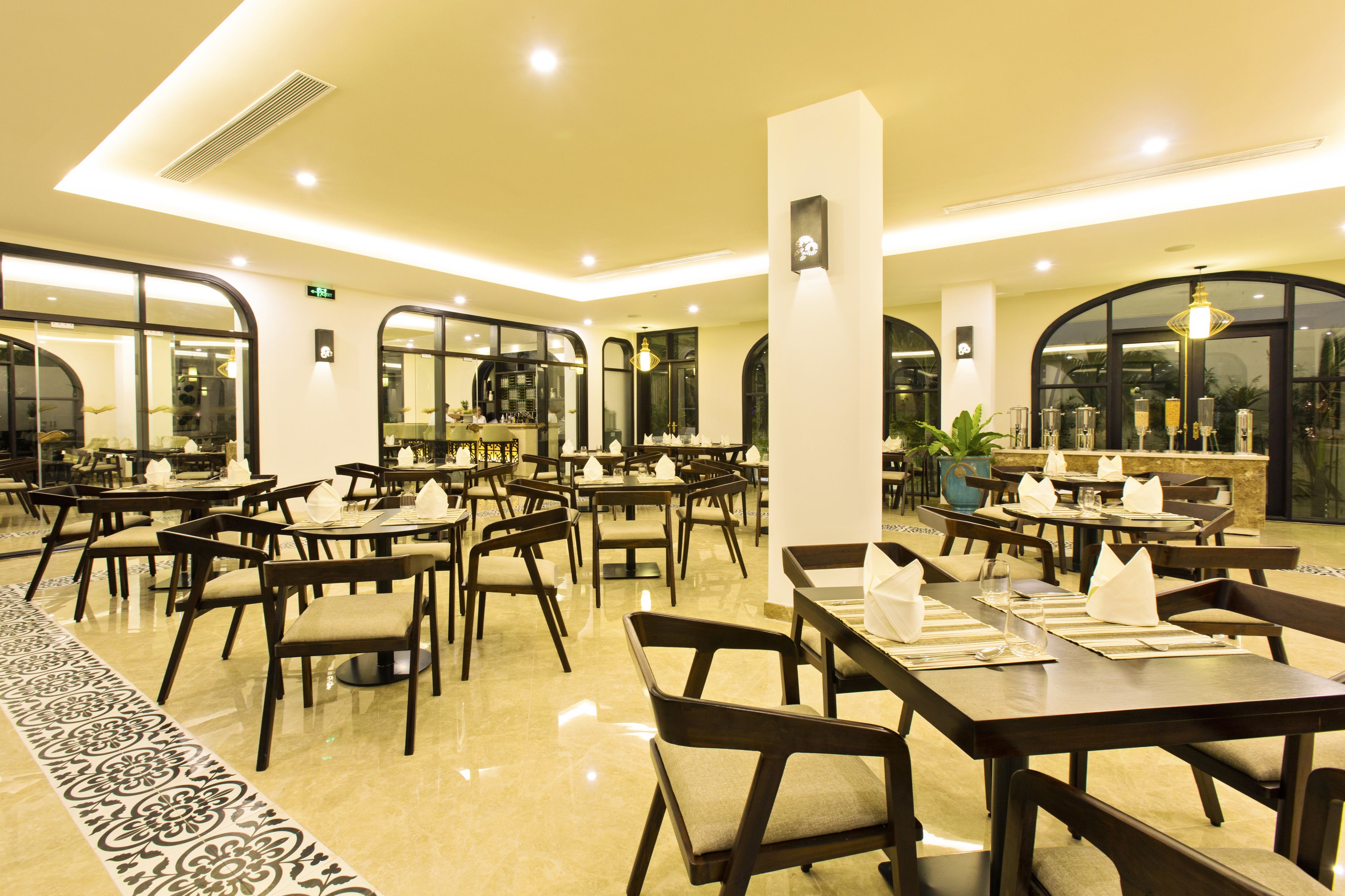 A spacious restaurant with multiple tables and chairs, large windows, and a clean, modern interior.