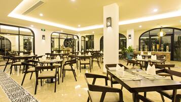 Un restaurant spacieux, doté de nombreuses tables et chaises, de grandes fenêtres et d’un intérieur propre et moderne.