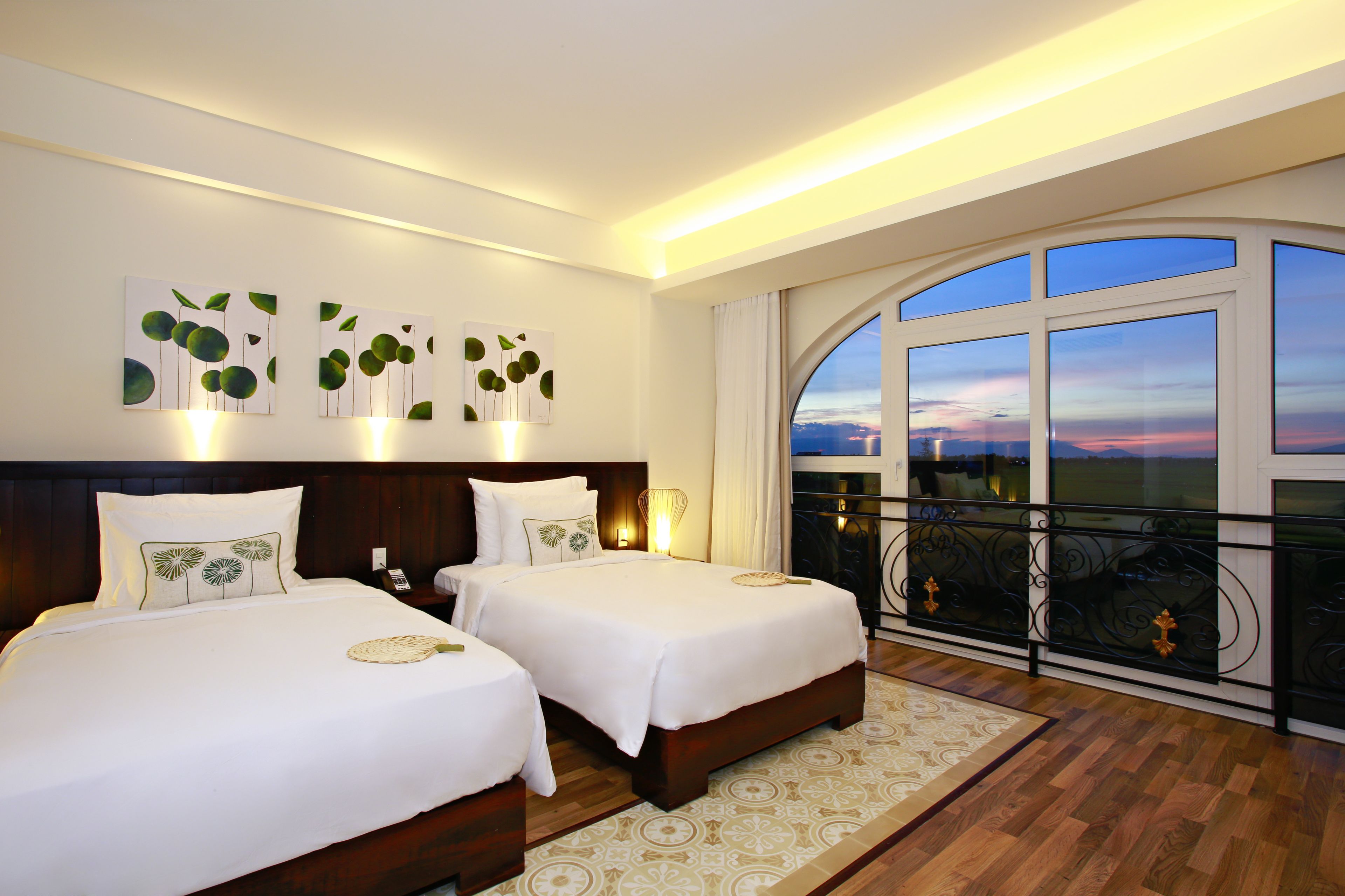 A hotel room with two beds, a large window with a view, and wall art.