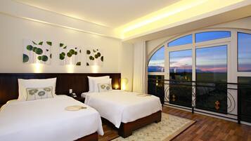 Una camera d'albergo con due letti, una grande finestra vista e opere d'arte alle pareti.