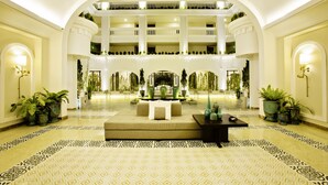 A spacious lobby with a central seating area, multiple balconies, and potted plants. - Lasenta Boutique Hotel Hoian (Da Nang)