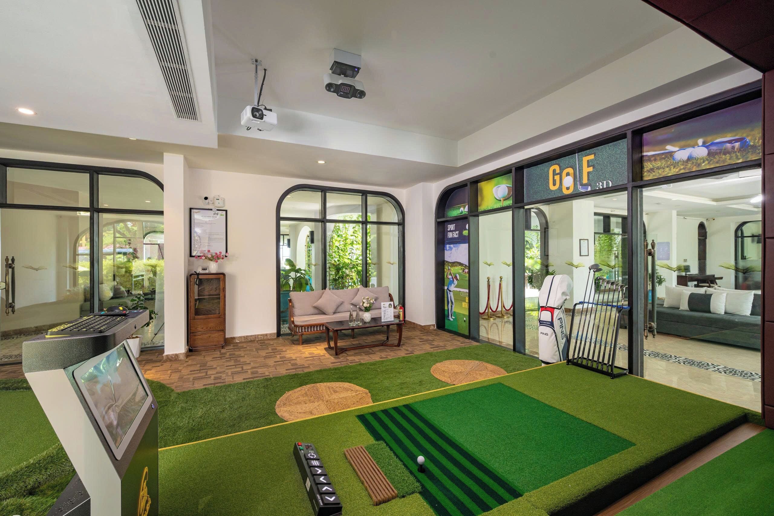 Ein Zimmer mit Golf-Simulationsbereich, einer Couch, einem Couchtisch und einem großen Fenster mit Blick auf Grünflächen.