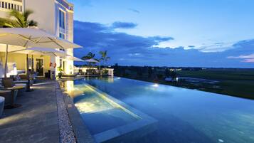 Alberca al aire libre, sombrillas en la alberca y camastros