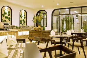 A restaurant with tables set for dining, a coffee machine, and decorative plants. - Lasenta Boutique Hotel Hoian (Da Nang)