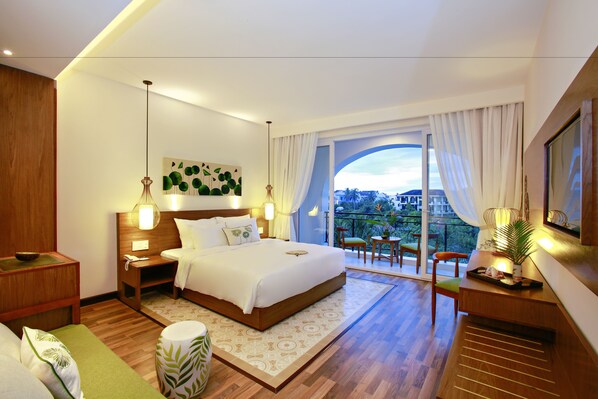 A modern hotel room with a large bed, a balcony with a view, and a dining area.