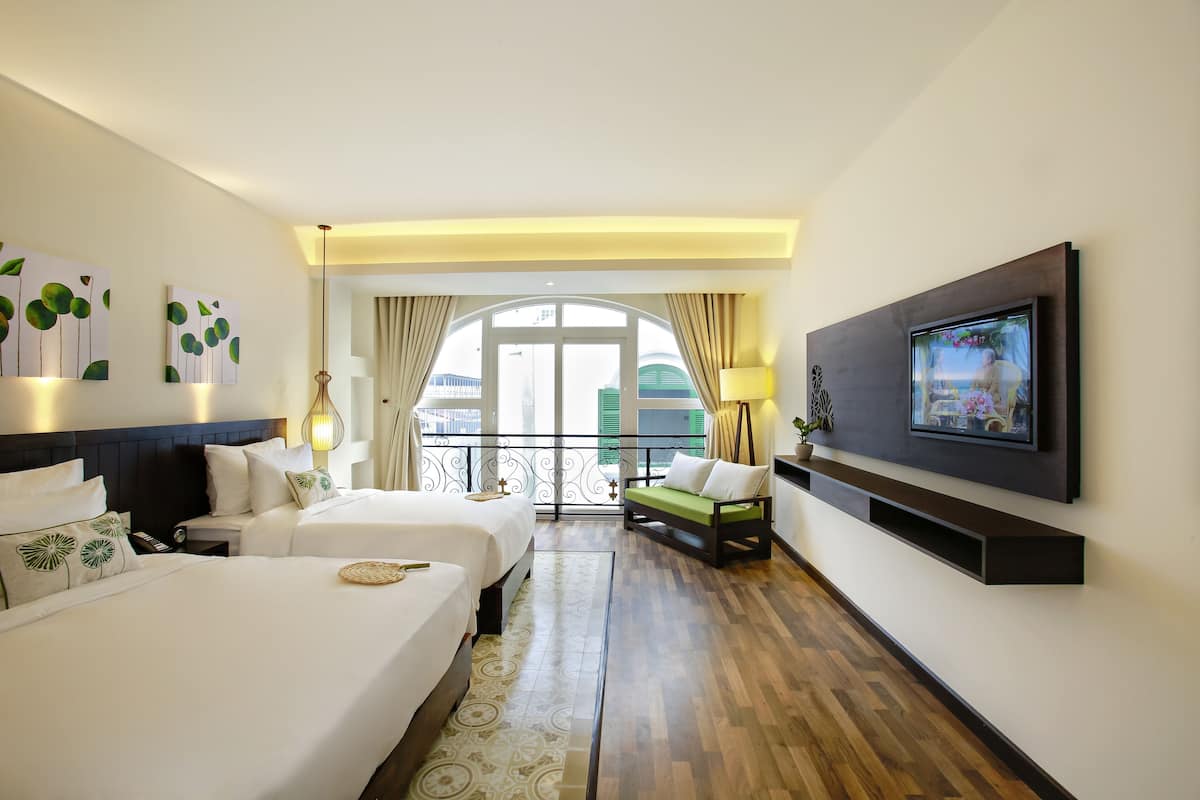 Une chambre d’hôtel avec deux lits, une télévision, un balcon avec vue et une grande fenêtre avec des rideaux.